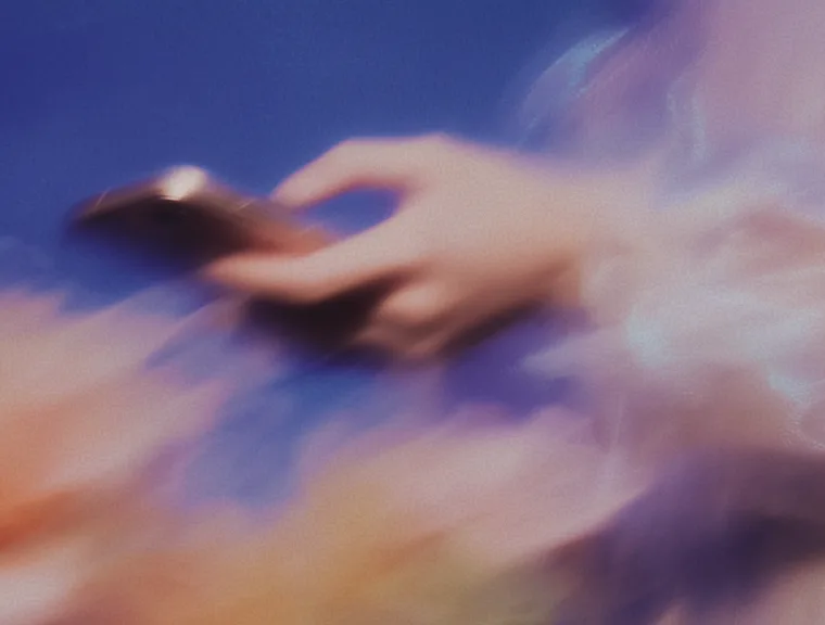 Woman in patterned suit floating while typing on a laptop, with digital code projected behind her on a pink background.