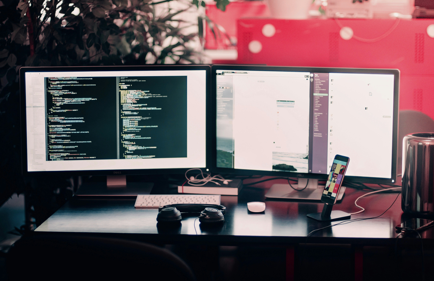 Photo of a dual-monitor coding setup with a code editor open in a red-lit office