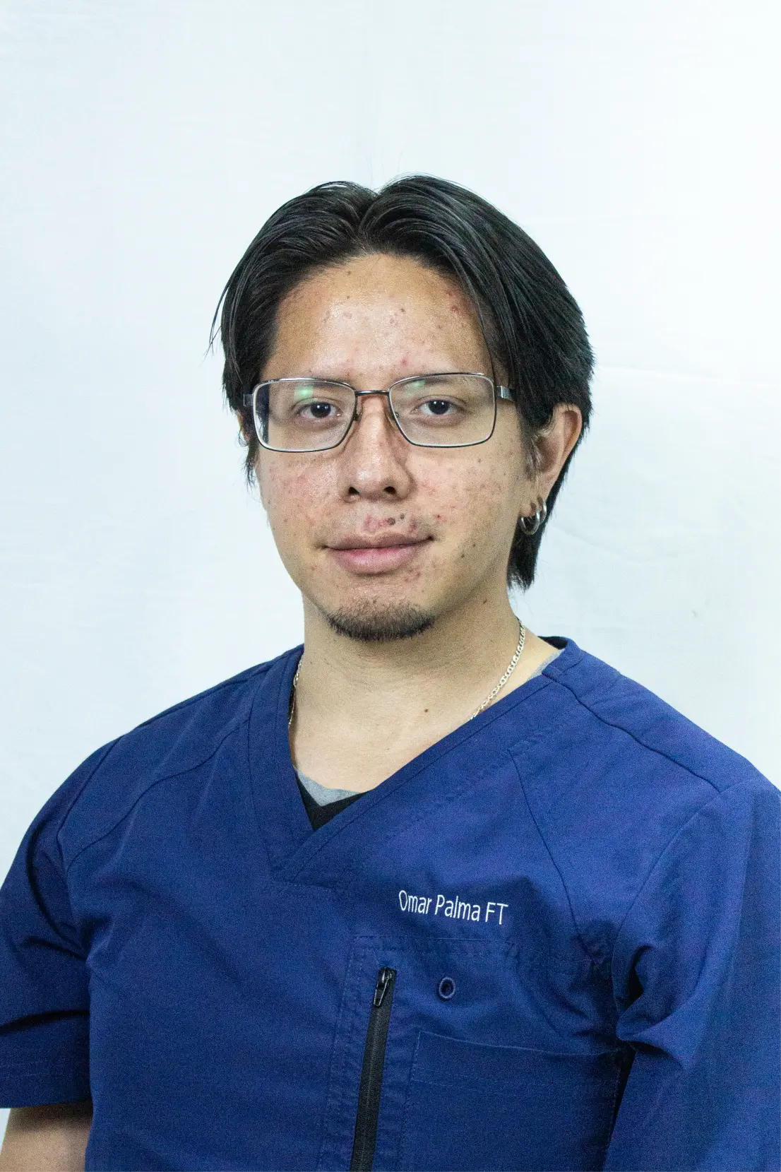 Man with glasses and dark hair wearing a blue medical scrub top with the name Omar Palma FT embroidered.