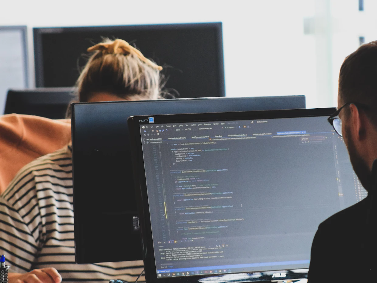 Two people working on code at their monitors