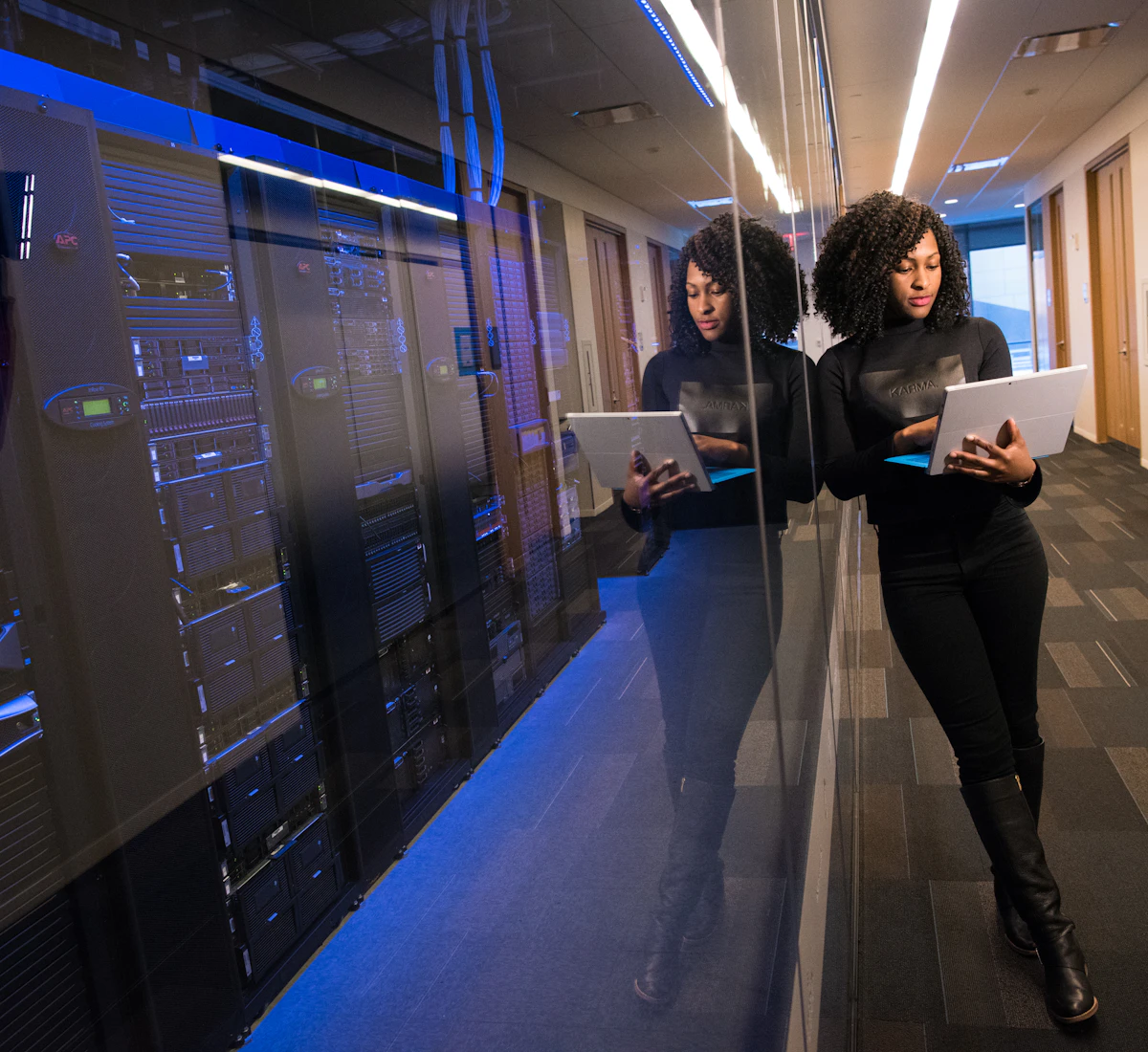 IT professional with a laptop beside modern server racks in a data center