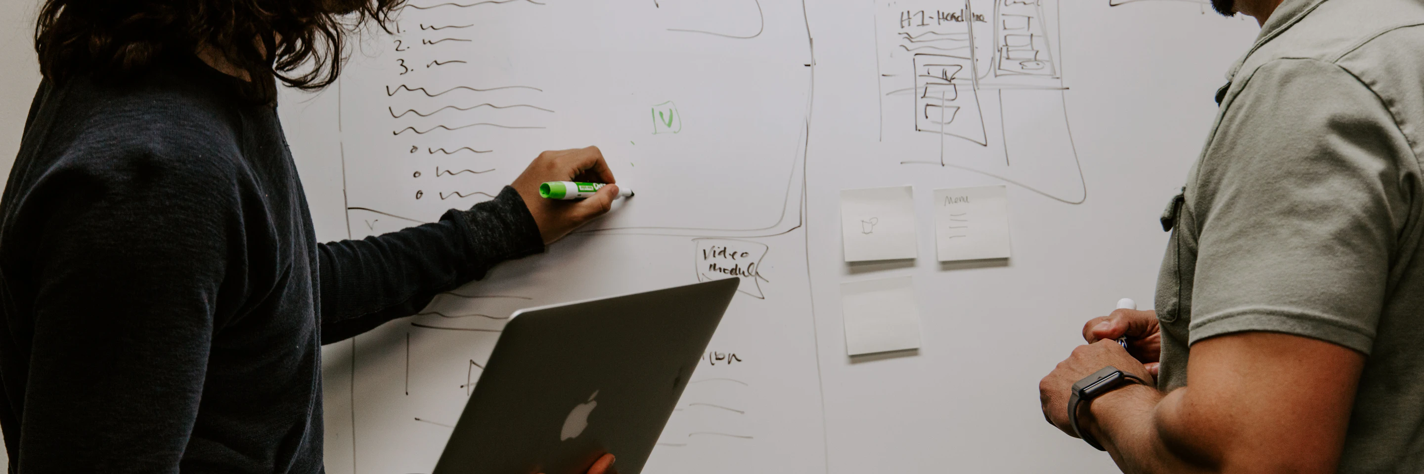 Two colleagues planning next steps at a whiteboard