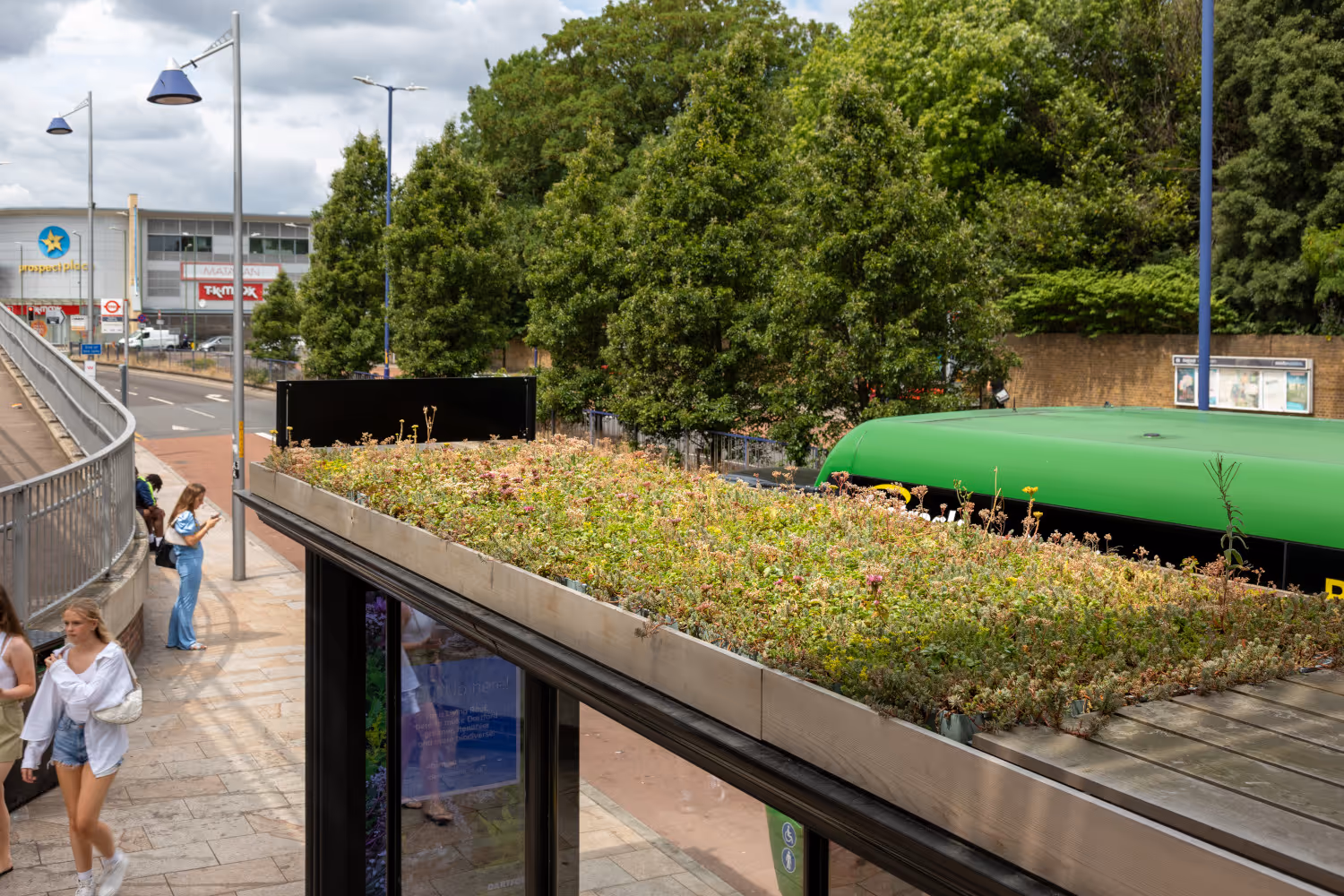 A Bauer Media Outdoor Living Roof bus shelter in Dartford during the day at a busy junction