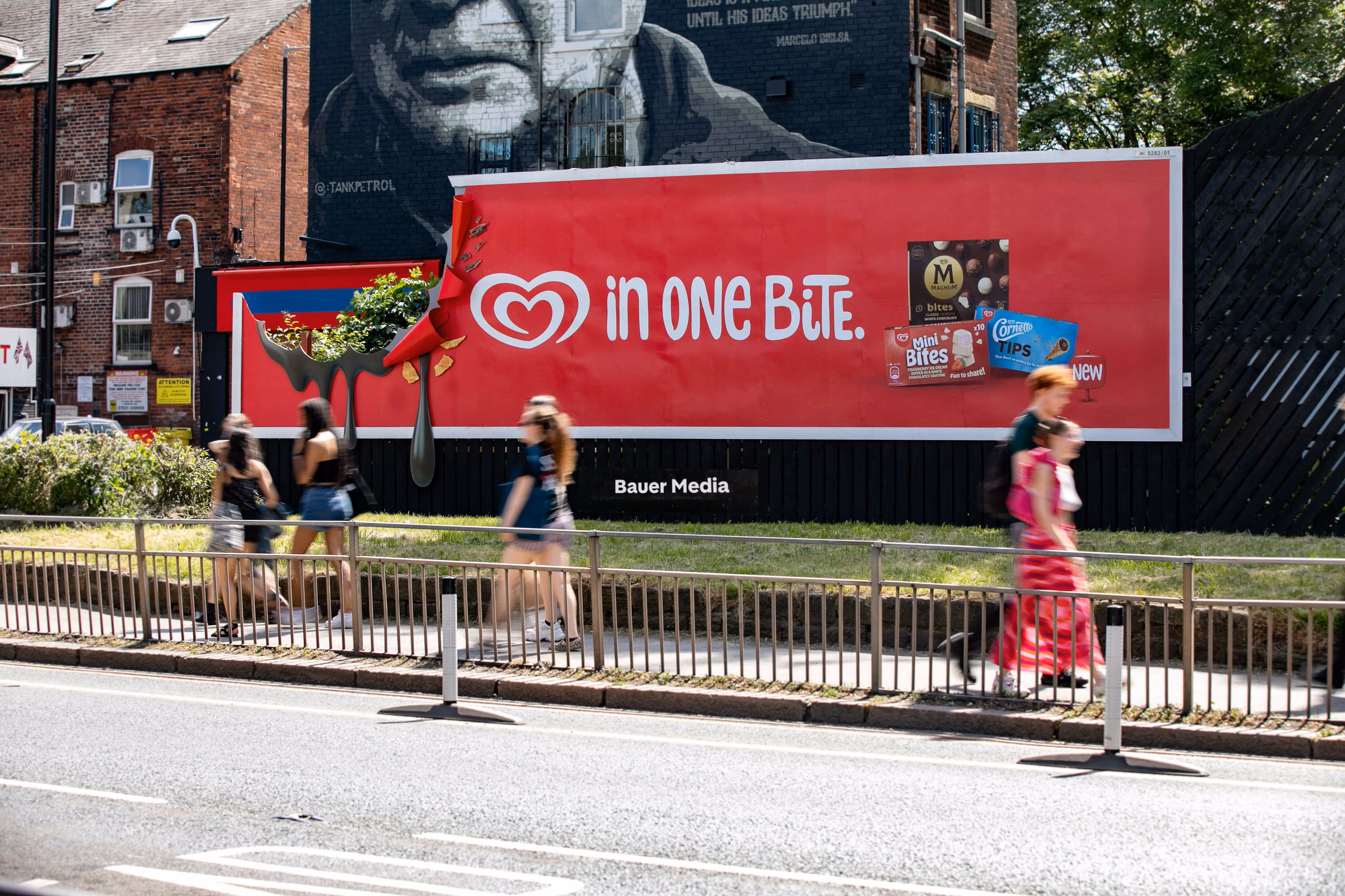 Bauer Media Outdoor roadside billboard displays a bold red Wall’s ice cream ad promoting bite-sized treats with the slogan “in ONE BITE".