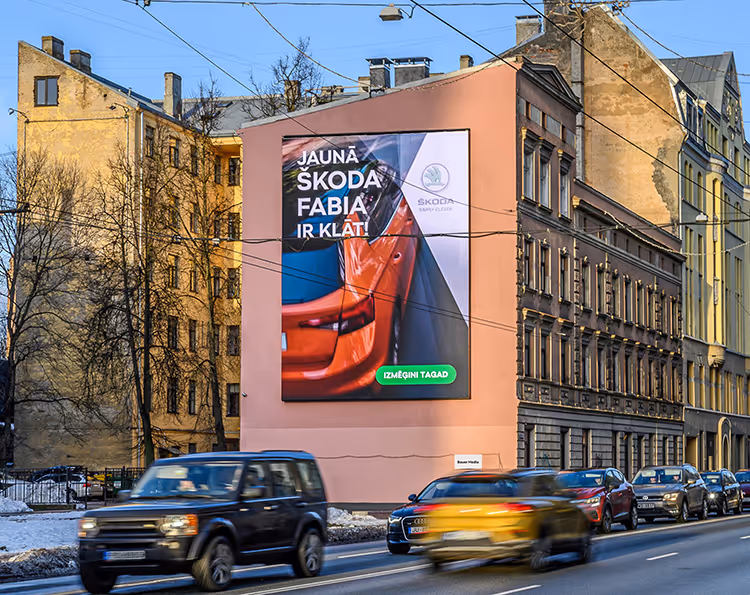 A large billboard for Skoda on a wall. It's a DOOH billboard. Cars drive past.