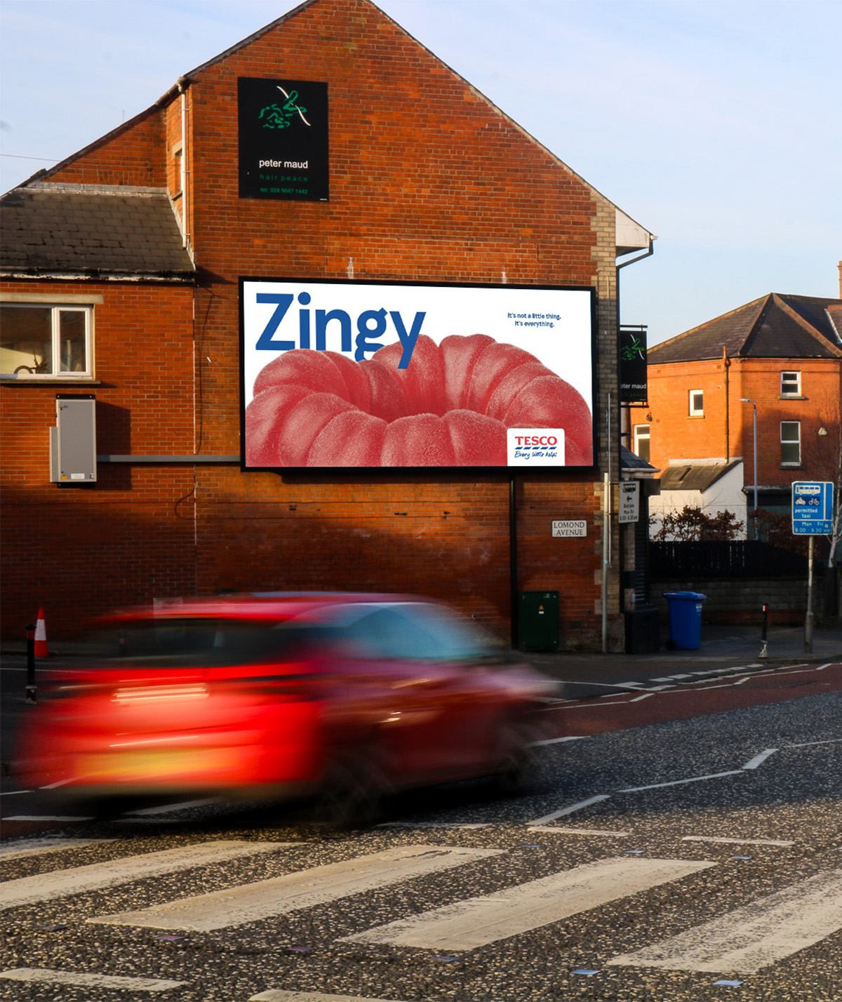 A Tesco digital billboard advert on the side of a building with a zebra crossing in front.