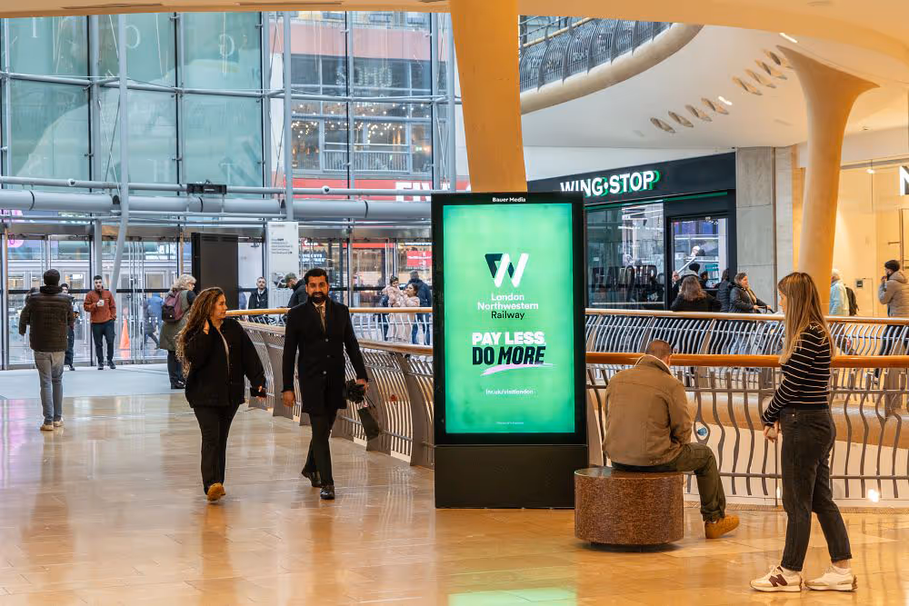A railway ad campaign inside a shopping mall with shoppers walking by