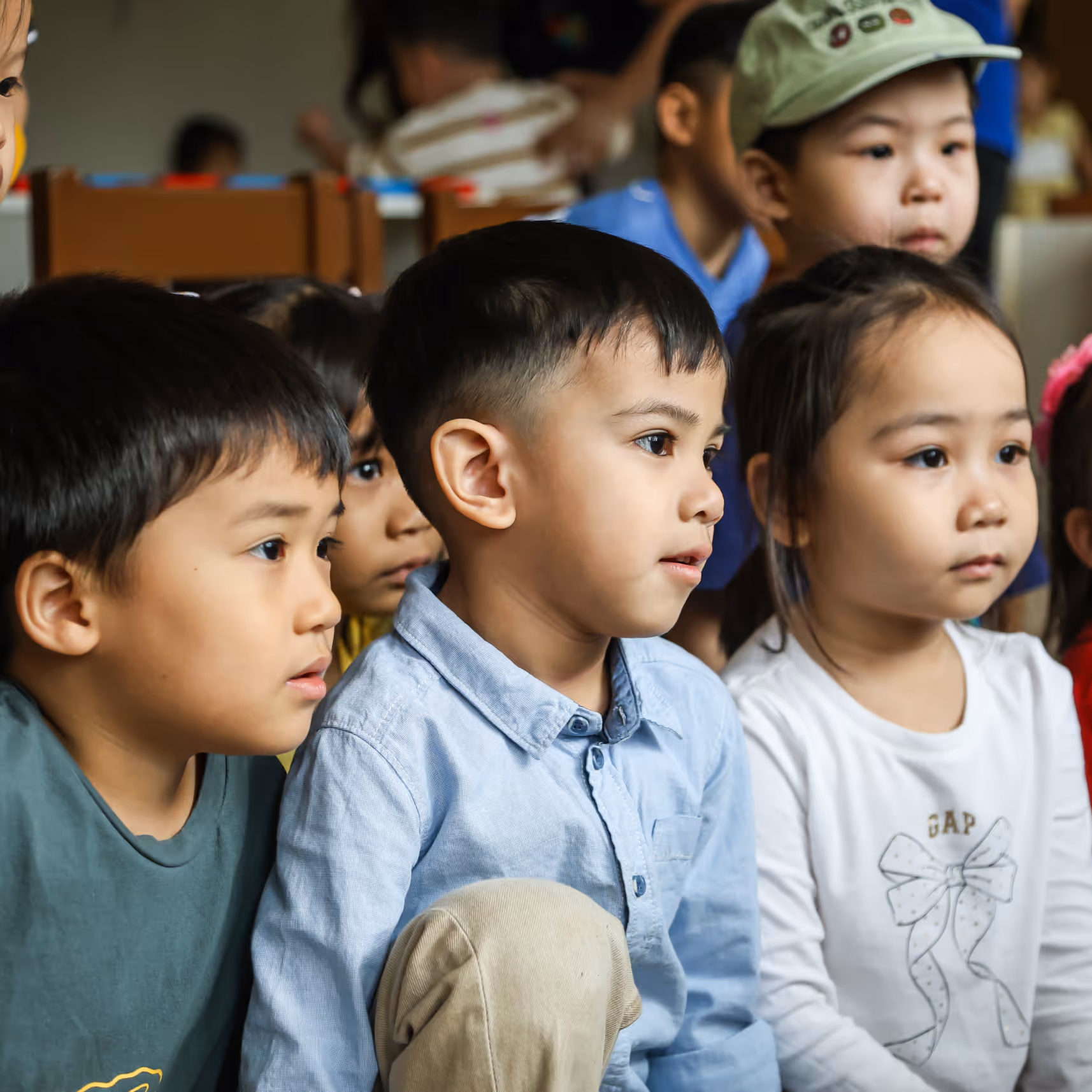 Group of attentive young children sitting closely together indoors.