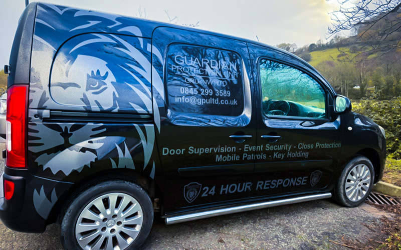 Black security van with a lion graphic and text advertising Guardian Protection Unit services including door supervision, event security, mobile patrols, and 24-hour response.