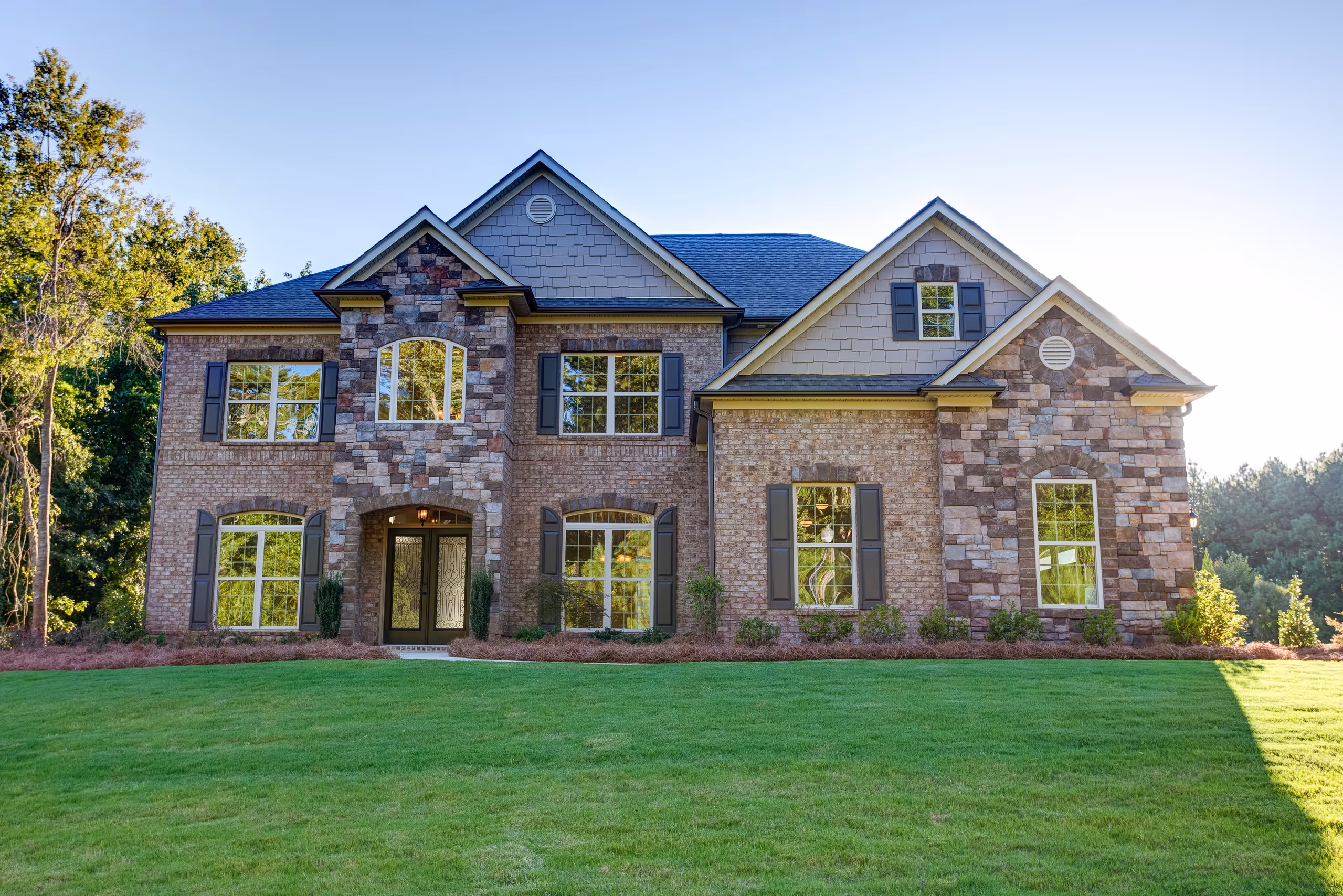Two-story stone and brick home film location in metro Atlanta with a large green lawn
