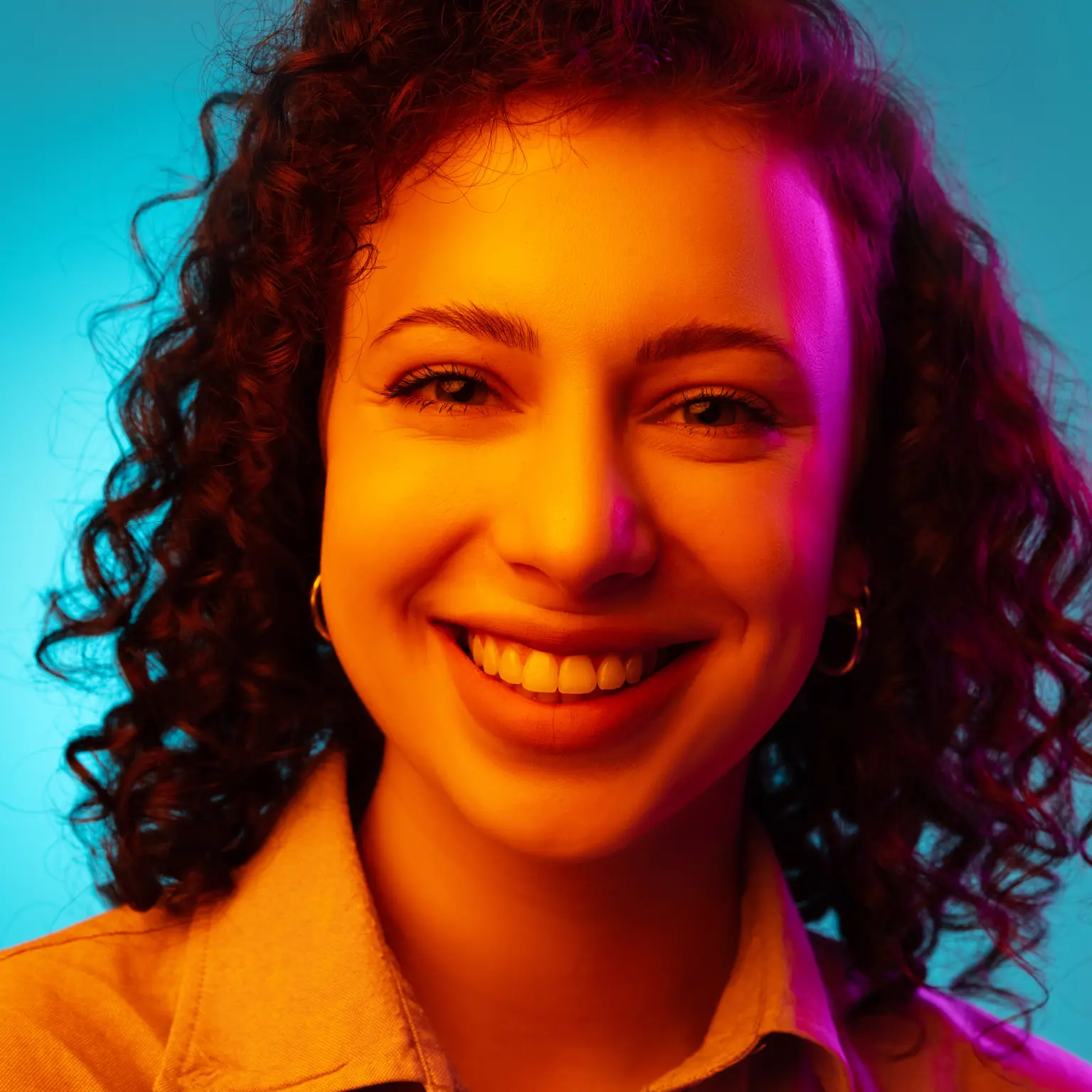 A happy woman with curly dark hair, smiling.