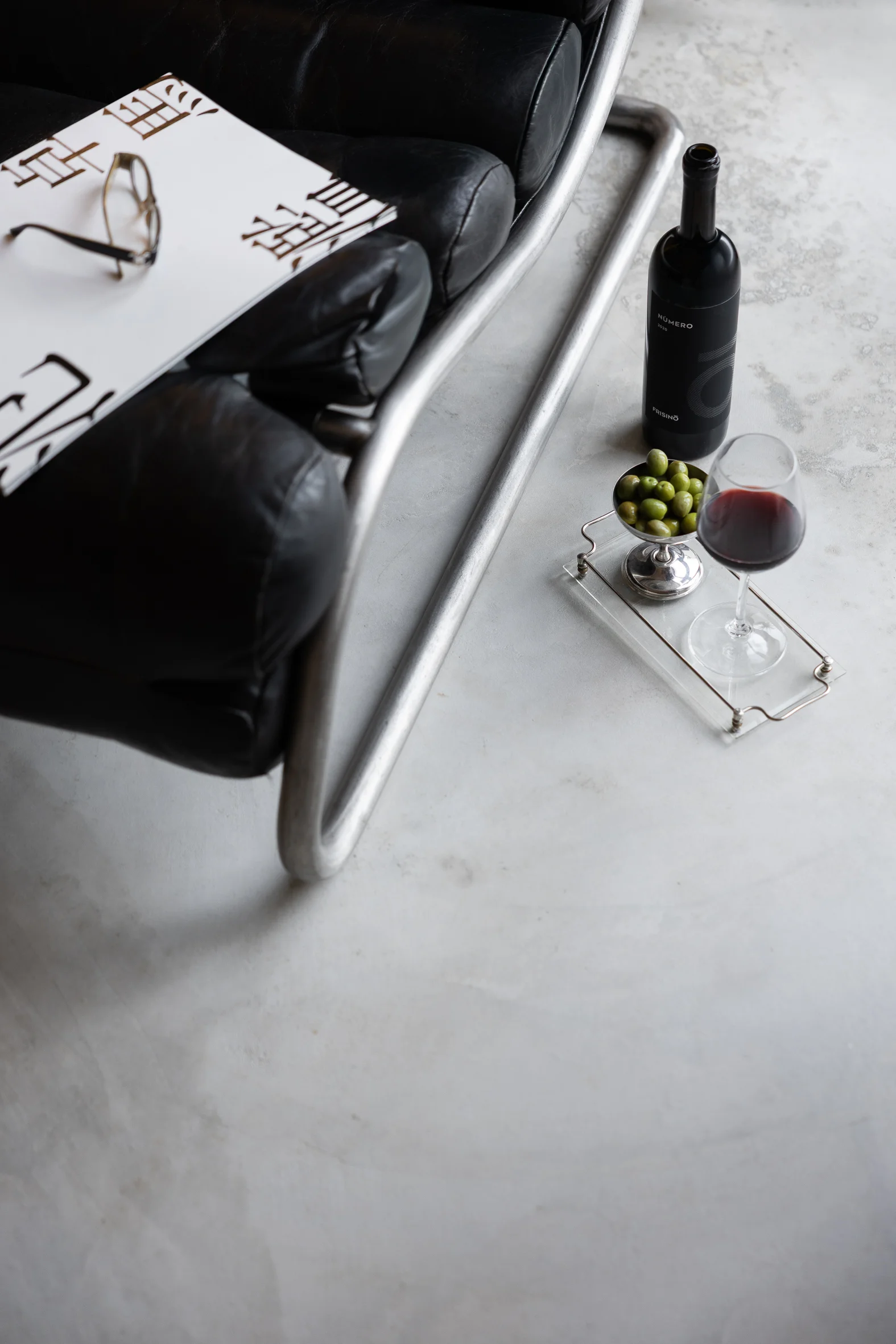Vineyard rows leading to a white rustic building with a forested hill in the background under a clear sky.  Frisino - Masseria Vallenza