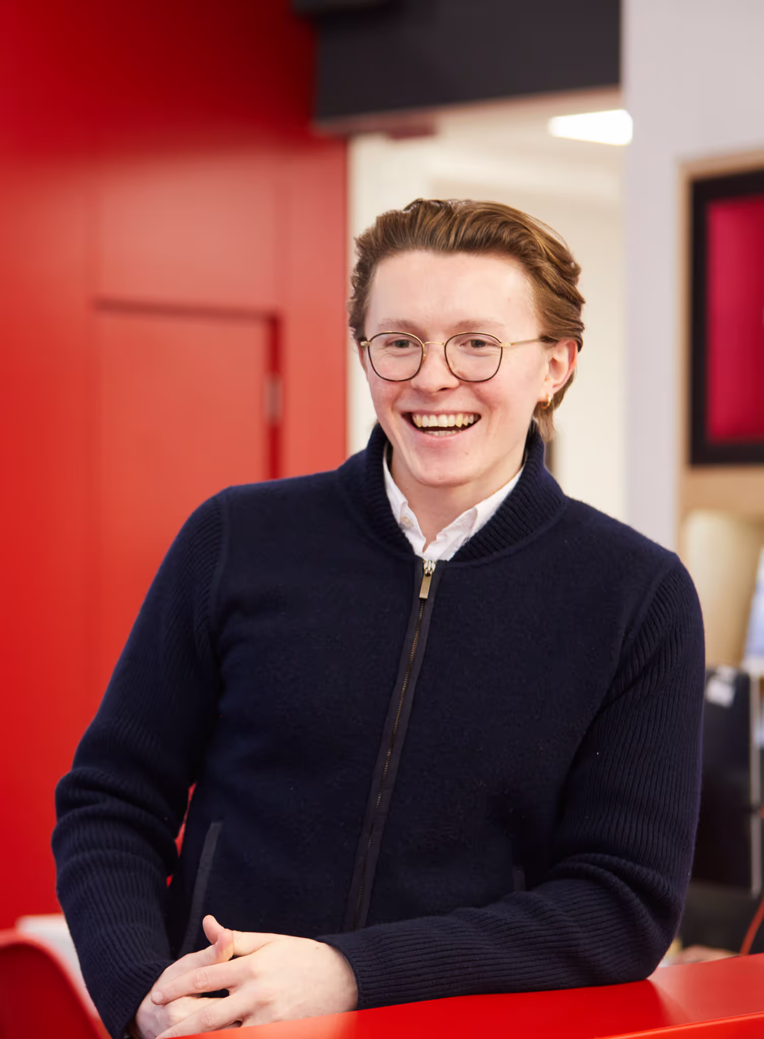 Friendly Male Flight Centre staff leaning on desk and smiling