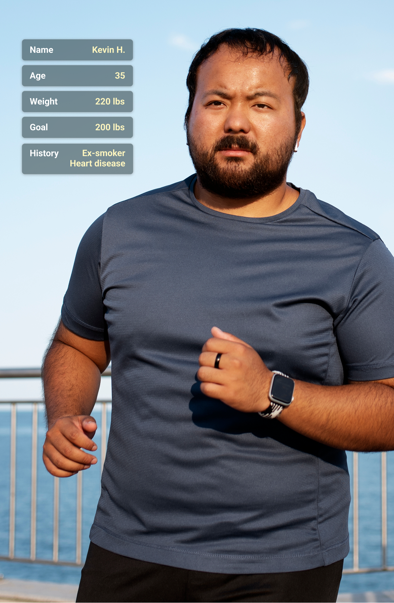 Man jogging outdoors near a railing with ocean in the background, wearing a dark gray t-shirt and smartwatch.