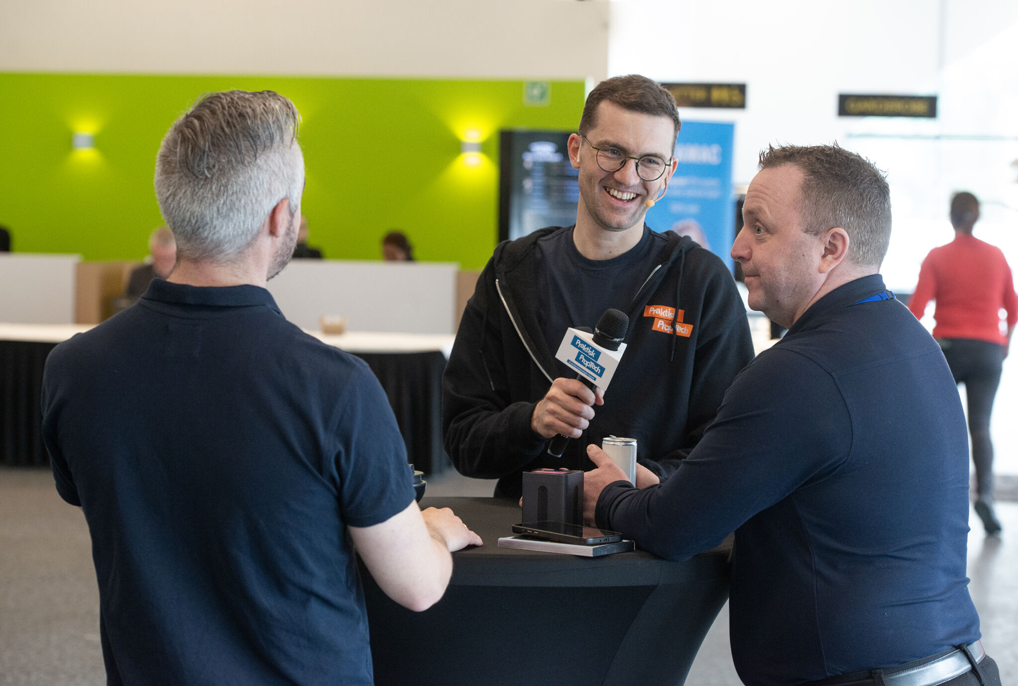 Praktisk PropTech host, Martin, holding a branded microphone while wearing a branded hoodie.