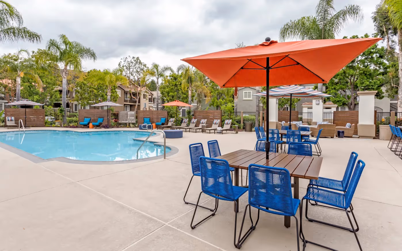 picnic table with umbrella in front of swimming pool