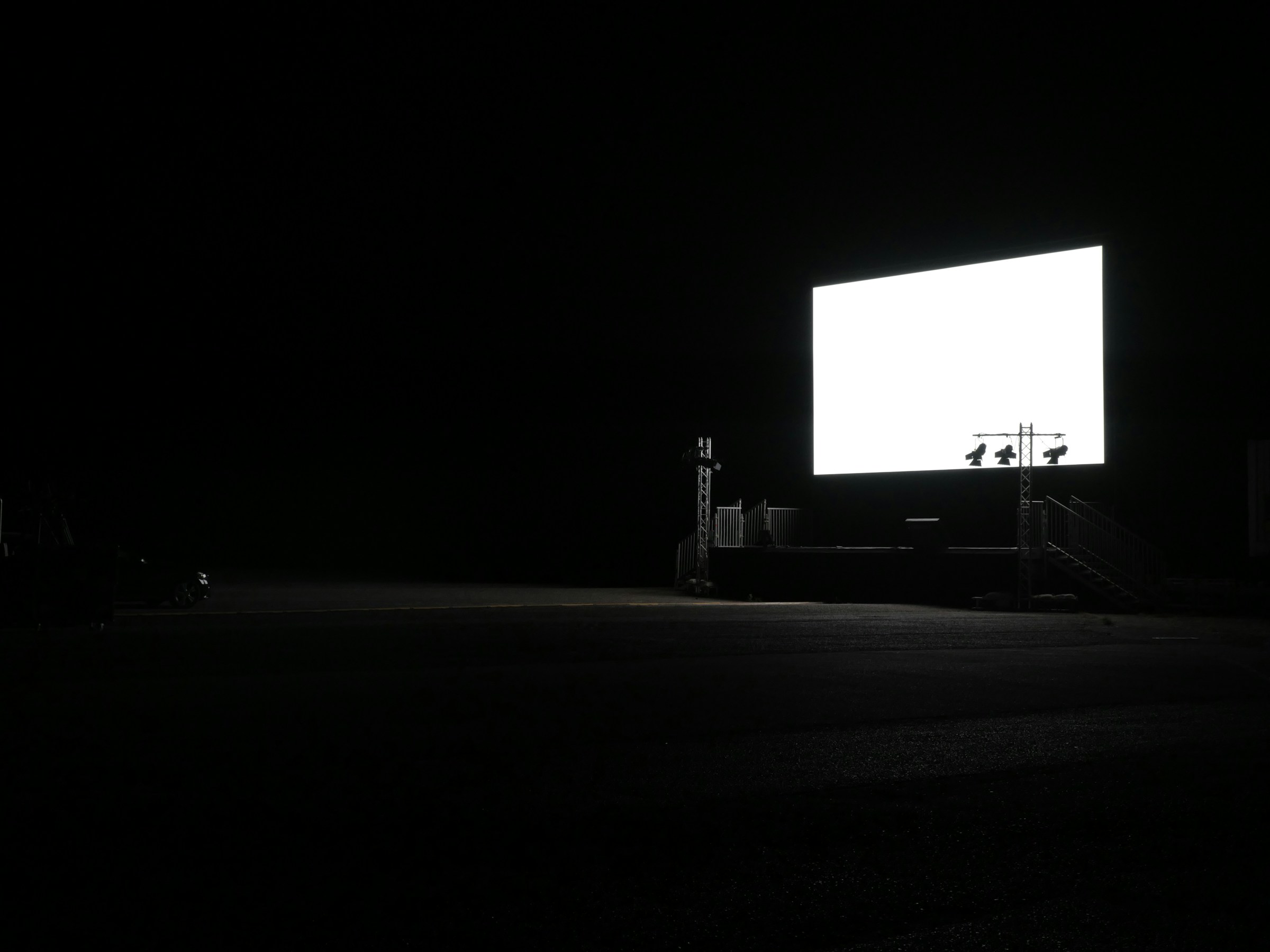 Large curved LED display wall at a brand activation event, audience in silhouette in the foreground