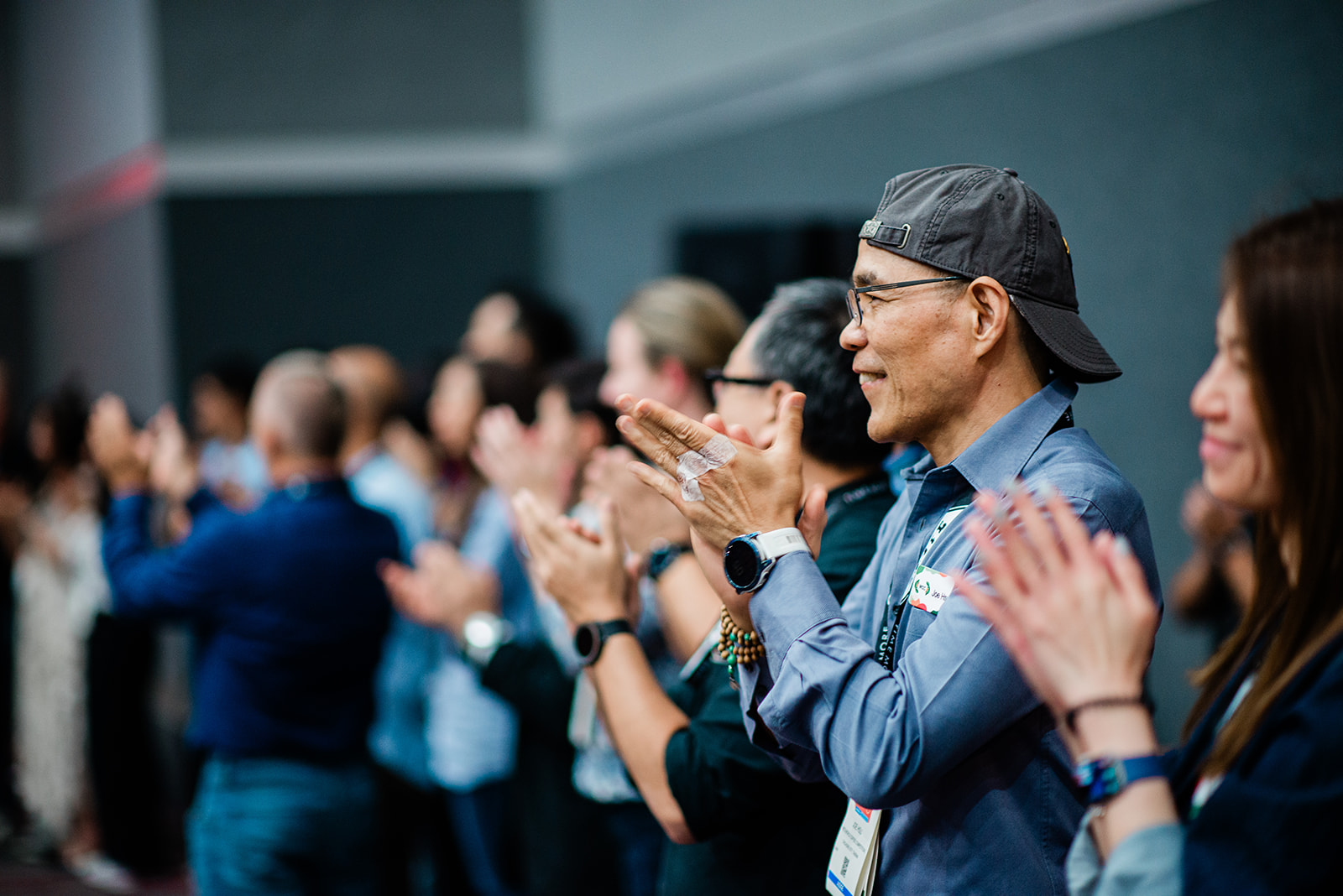 A diverse group of people standing and clapping in appreciation at an event.
