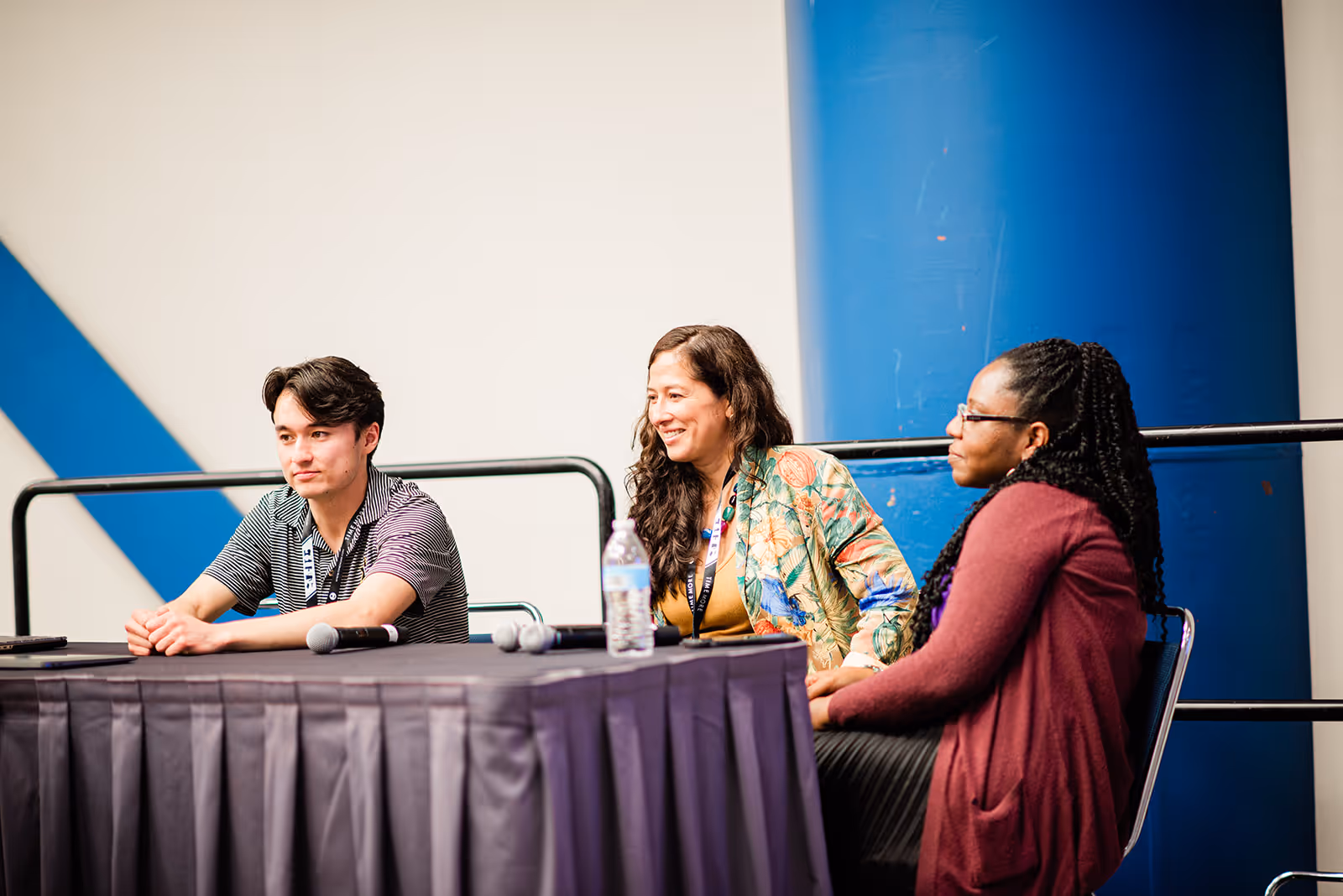 Three people sitting at a table with microphones, participating in a panel discussion.