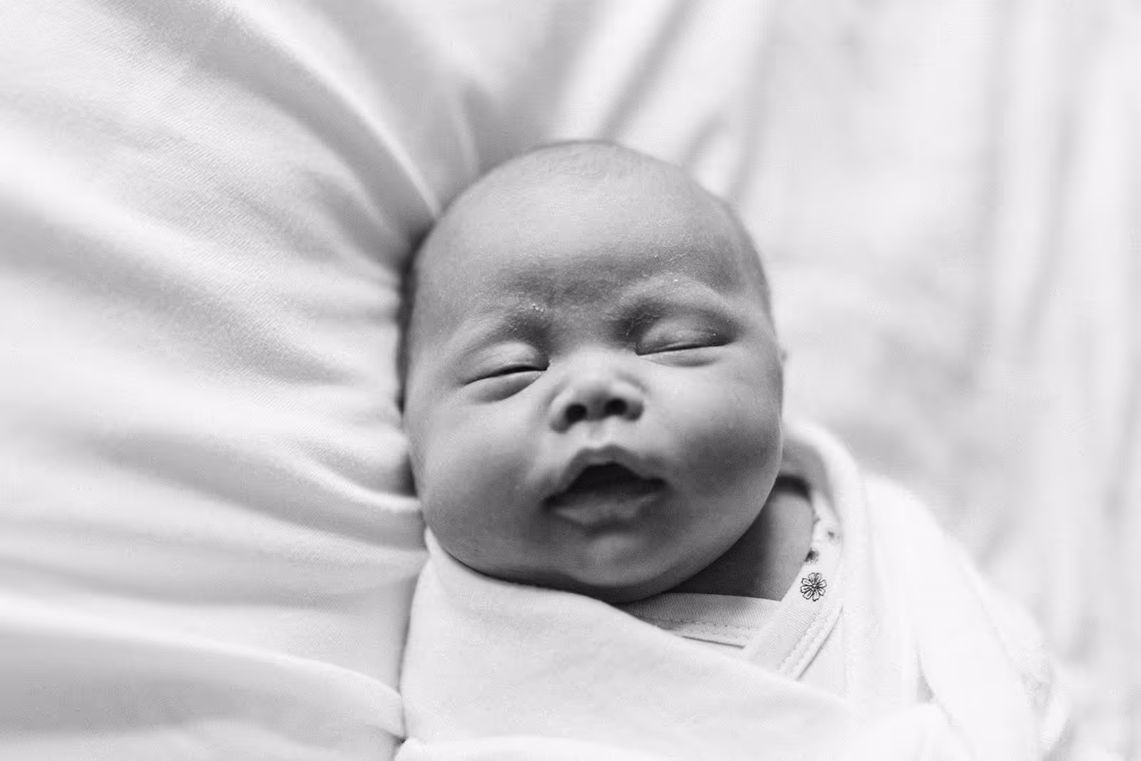 Close-up of a sleeping newborn baby wrapped in a blanket.