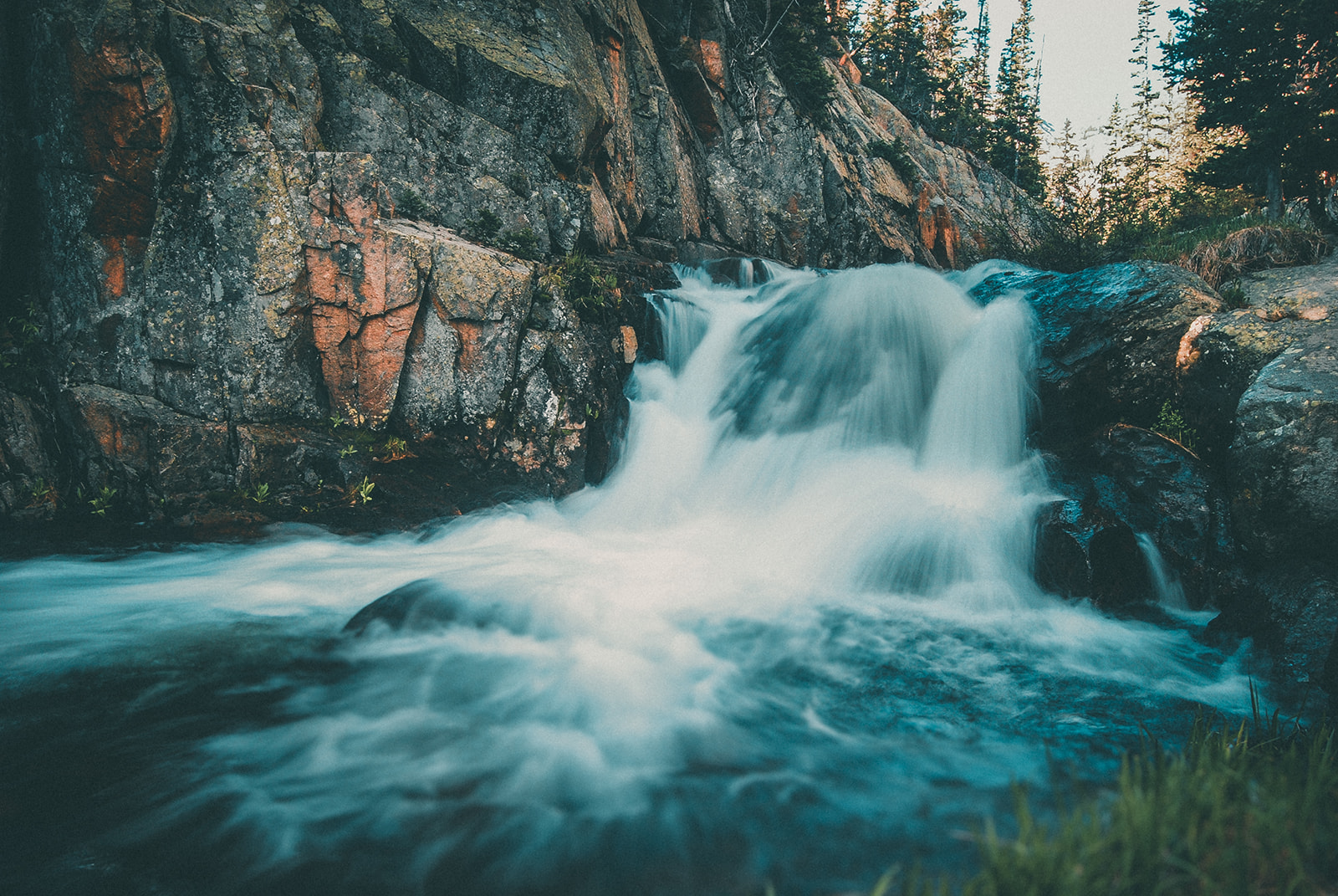 Small waterfall cascading over rocky terrain surrounded by trees.