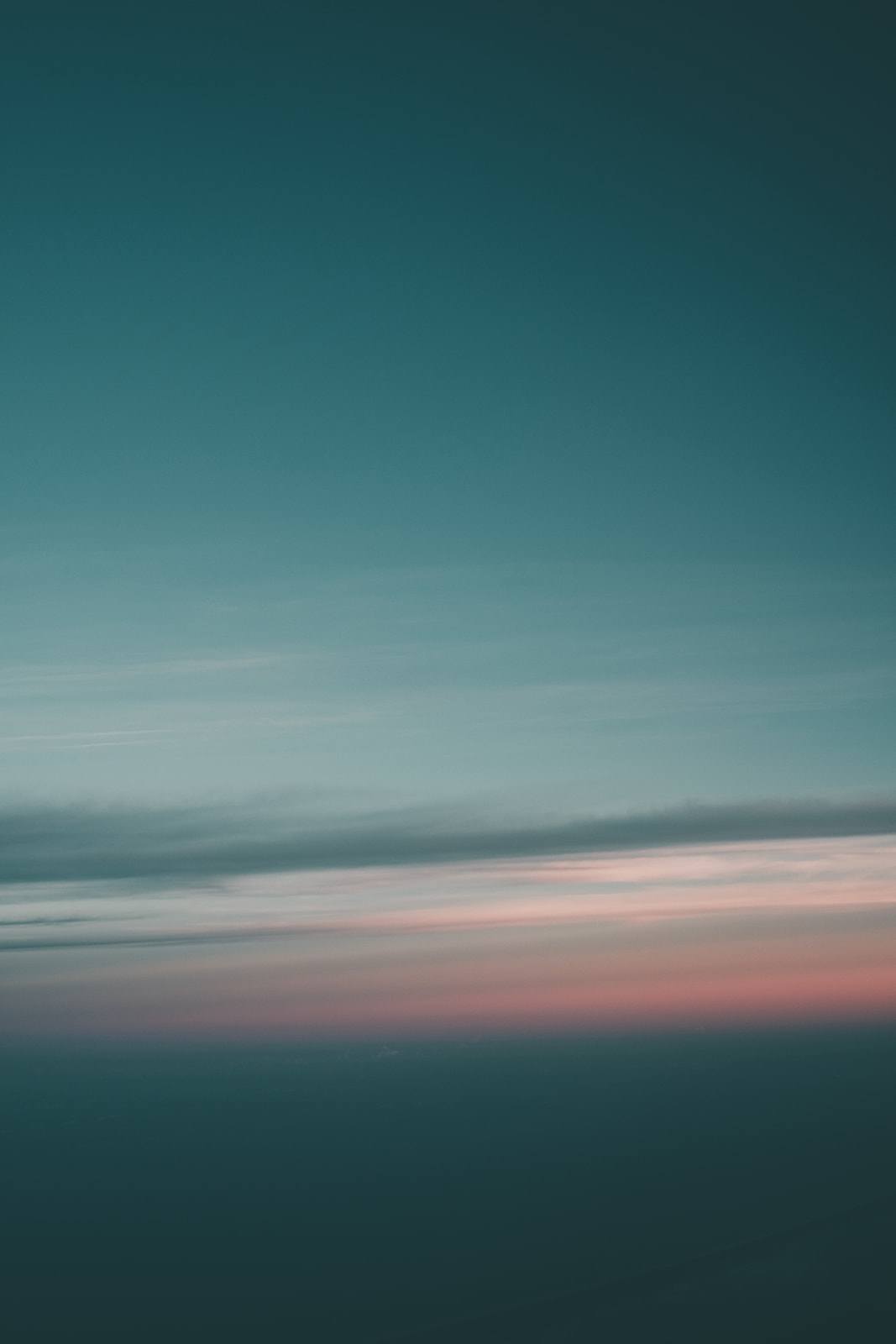 Sky with gradient colors from teal blue to soft pink near the horizon during twilight with thin, wispy clouds.