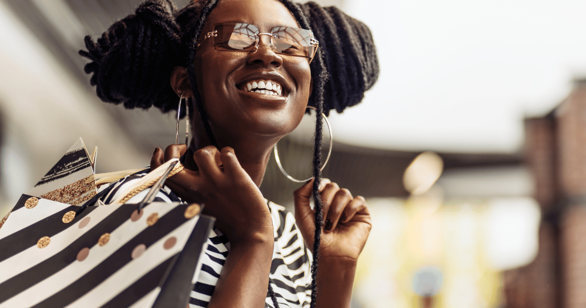 A young woman smiling to camera with shopping bags over her shoulder