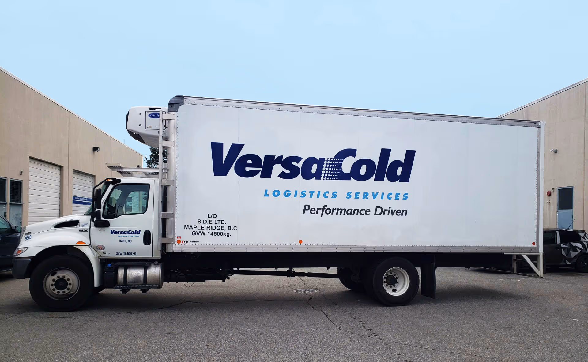 White refrigerated delivery truck with large VersaCold Logistics Services logo and 'Performance Driven' slogan on its side.
