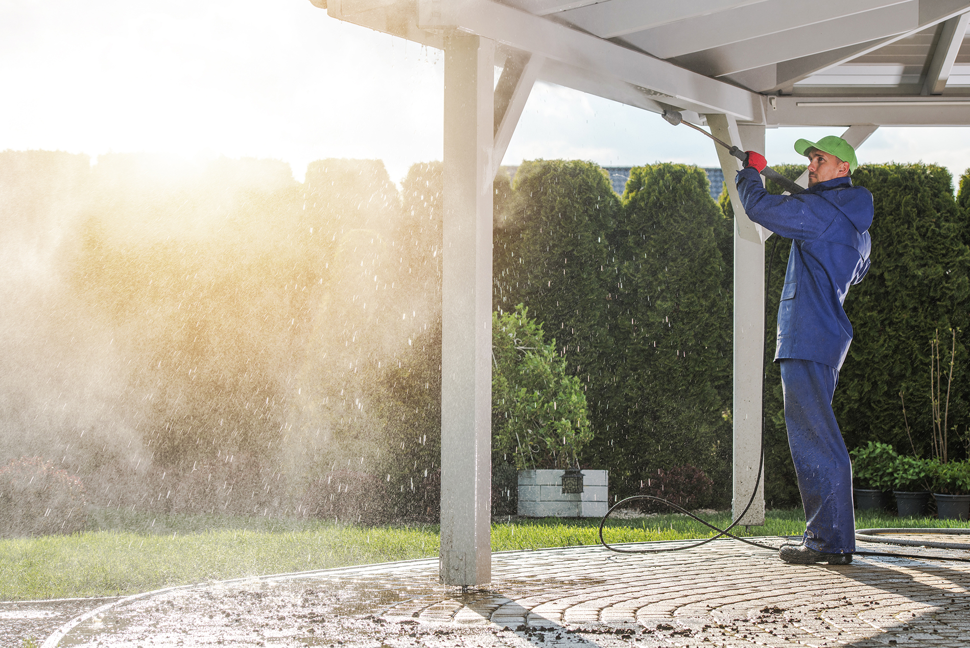 Worker power washing a beam outside.