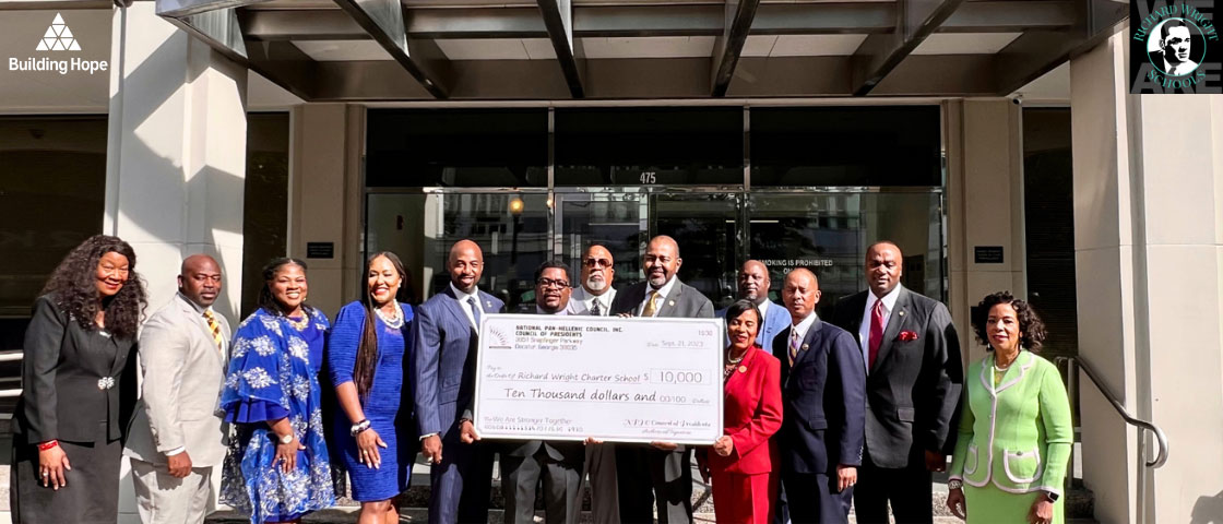 The National Pan-Hellenic Council holding a large $10,000 check at Richard Wright Schools, celebrating a donation and partnership with Building Hope for school growth and expansion.