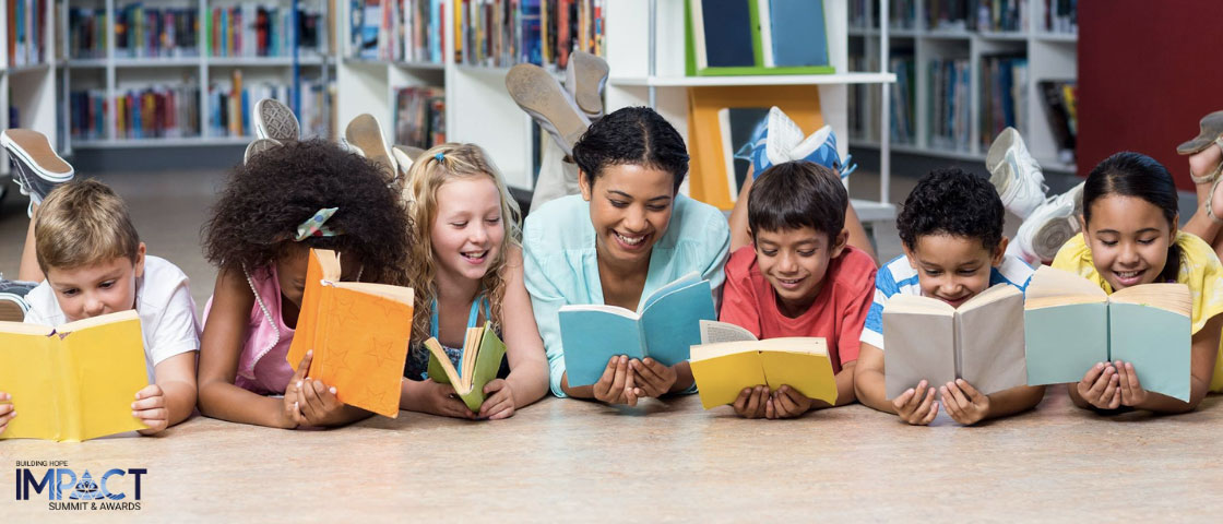 A group of students lying on the floor together, reading books and engaging in collaborative learning.