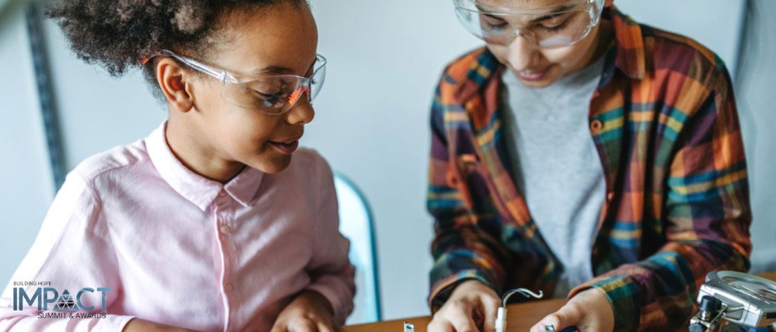 Two students wearing safety glasses working on electrical components in a science lab, demonstrating hands-on learning and innovation.
