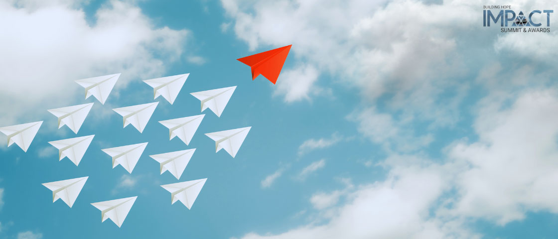 A red paper airplane leading a group of white paper airplanes, symbolizing leadership and innovation in schools.