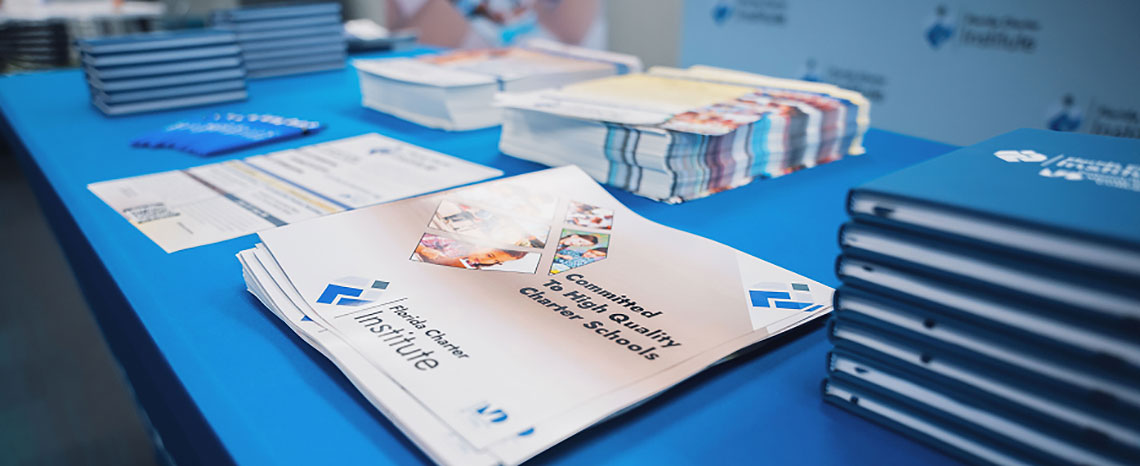 A table with educational brochures, notebooks, and flyers neatly arranged. The materials are branded with a logo, conveying a professional tone.