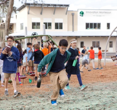 Children are playing energetically outdoors on a school playground, holding various items. The scene is lively, with a building labeled "Innovation Montessori" in the background.