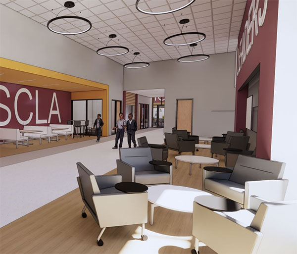 Modern lounge area with gray chairs and circular tables, under large ring lights. Three people converse in the background near a sign reading "SCLA".