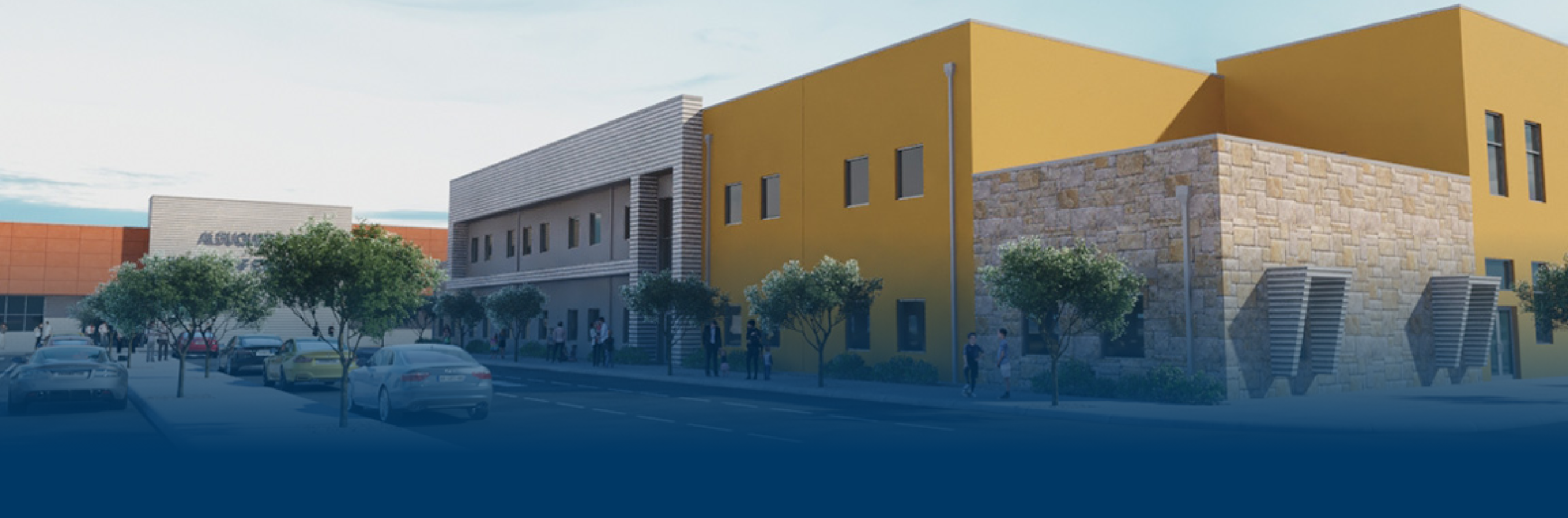 Modern building facade with yellow and stone walls, large windows, and trees. People are walking along the sidewalk on a sunny day.