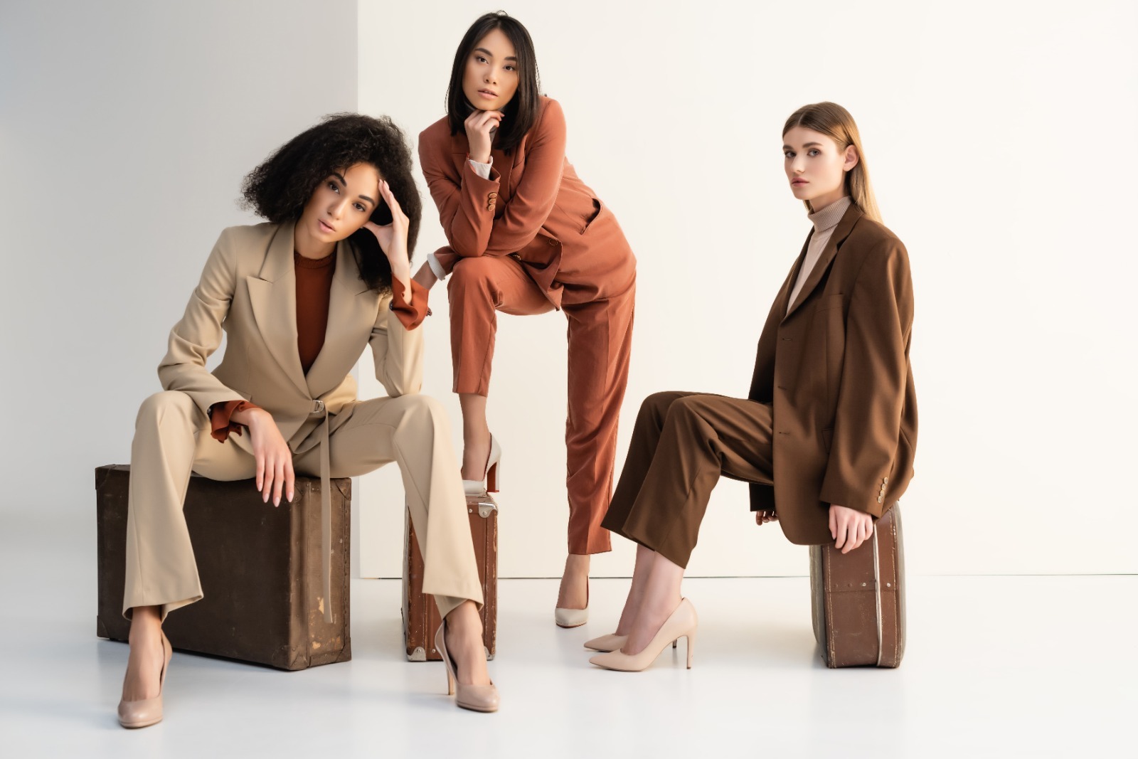 Three women demonstrating outfit balance, neutral basics paired with a bold rust-colored statement blazer