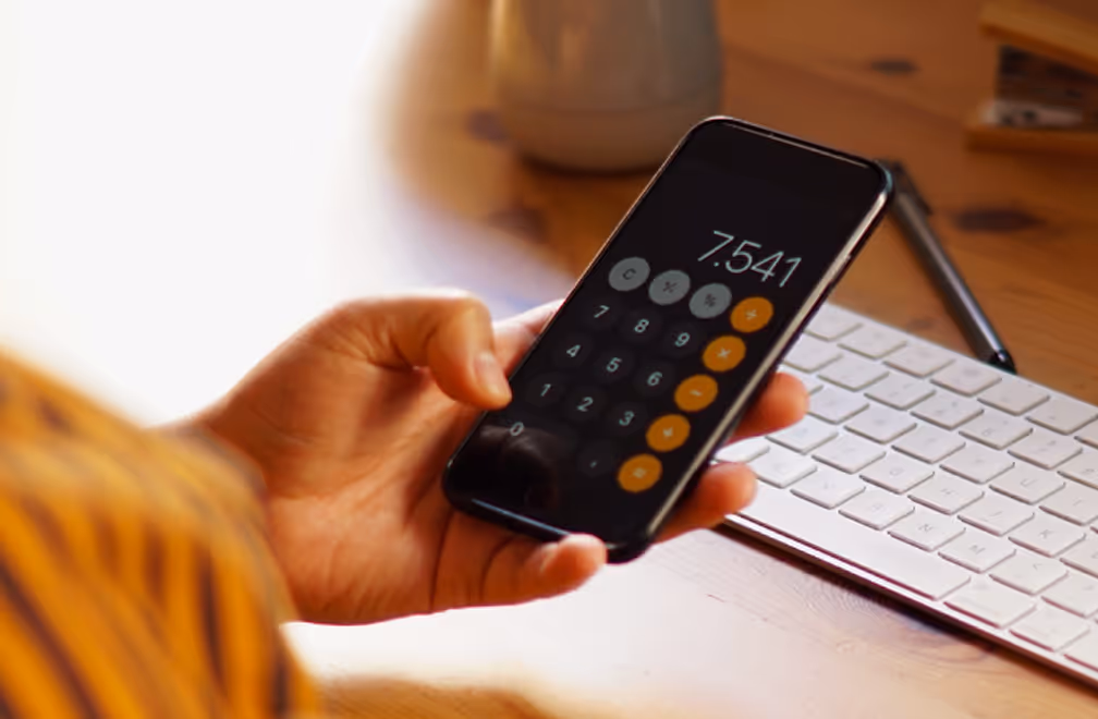 Pessoa segurando um smartphone com aplicativo de calculadora aberto