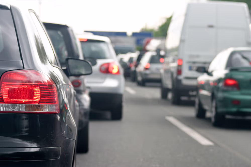 Traffic jam with multiple vehicles including cars and a white van on a multilane road.