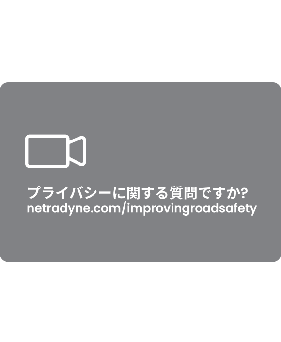 White video camera icon above Japanese text and web address netradyne.com/improvingroadsafety on a gray background.