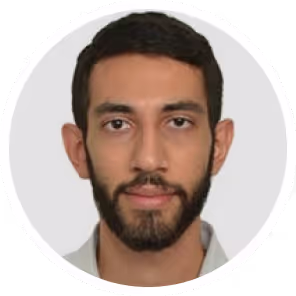Close-up portrait of a man with short dark hair, beard, and mustache, wearing a light-colored shirt.
