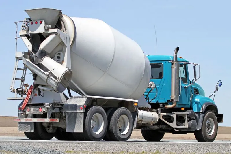 A concrete truck parked, the truck has a blue cab.