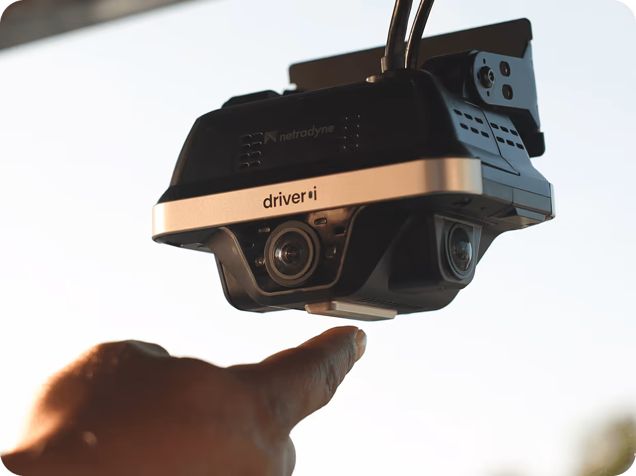 Close-up of a mounted Driveri dash camera with a hand pointing towards it.