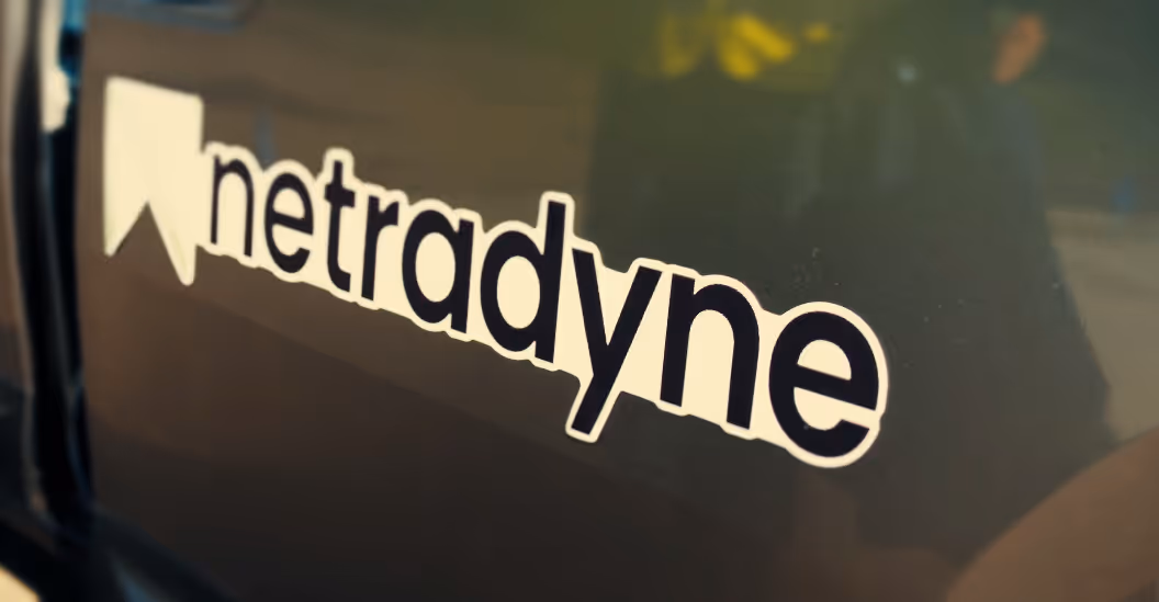 White and black sticker with the word 'netradyne' on a dark reflective surface.