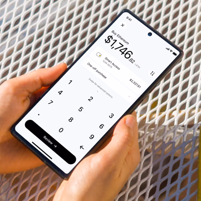 Person holding a smartphone showing an app screen to buy Ethereum with a numeric keypad and a review button.