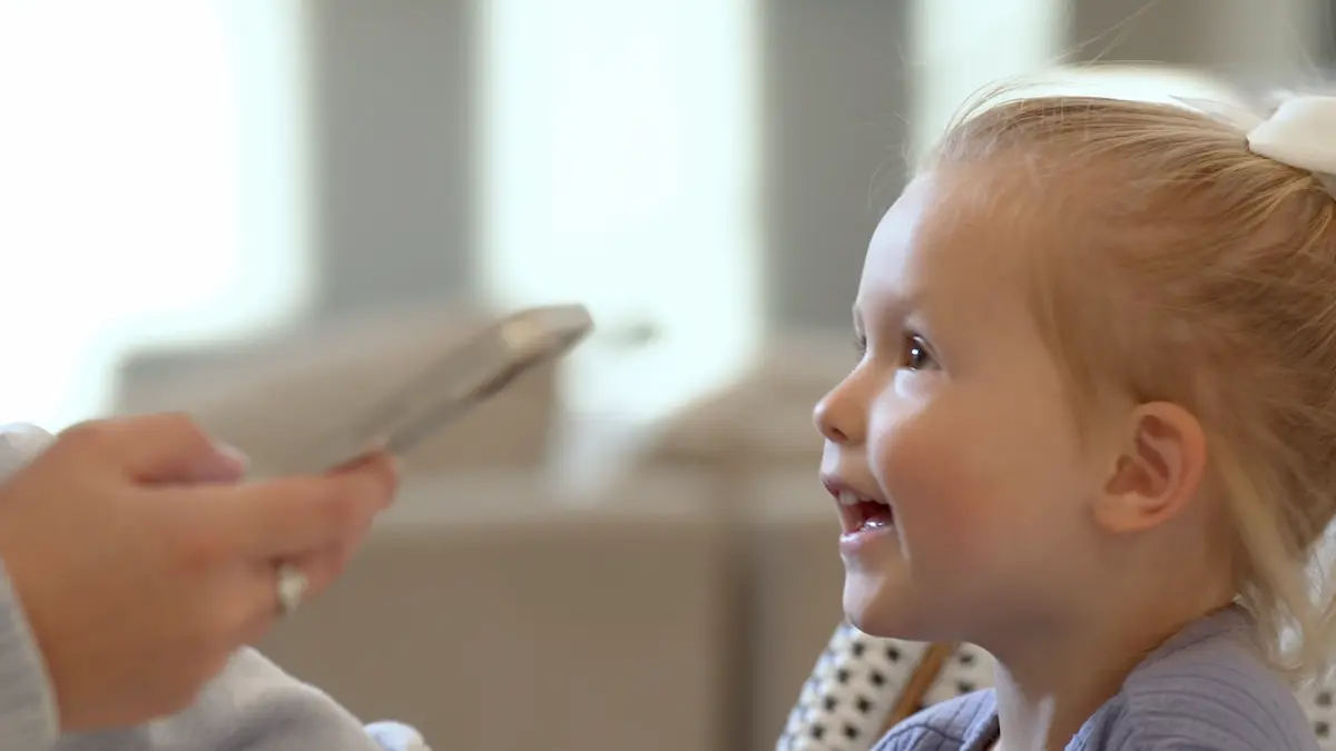A young girl happily looking up at her mother typing on a phone.