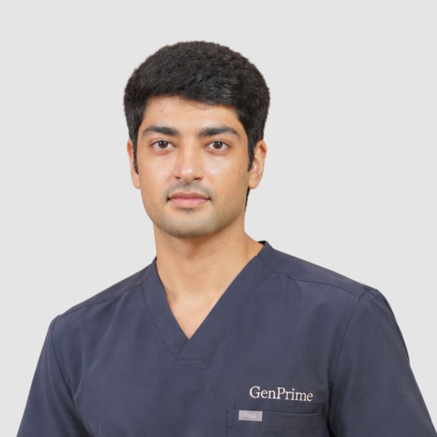 Head-and-shoulders portrait of a GenPrime junior embryologist in navy scrubs.