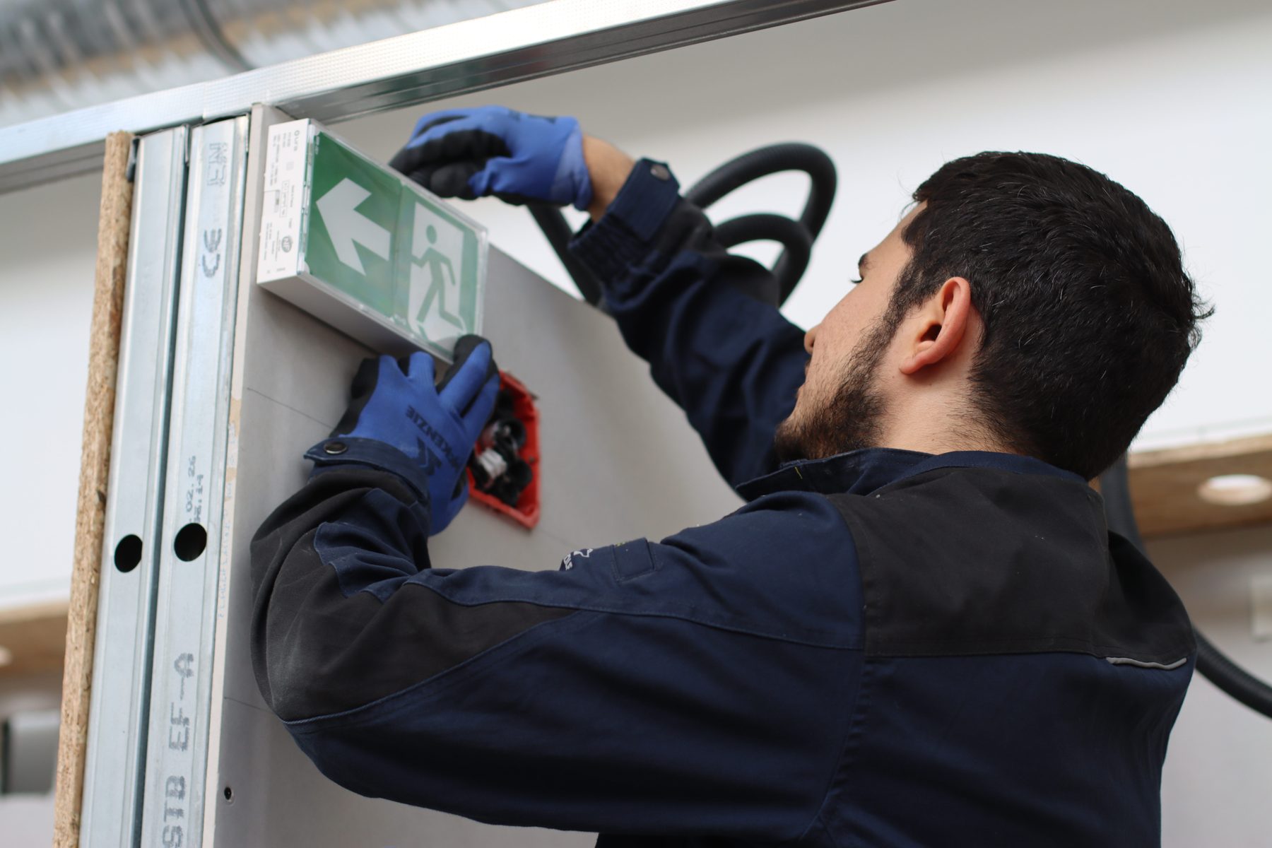 Apprenti agent de maintenance qui remplace un bloc d'éclairage de sécurité au Campus Arvo