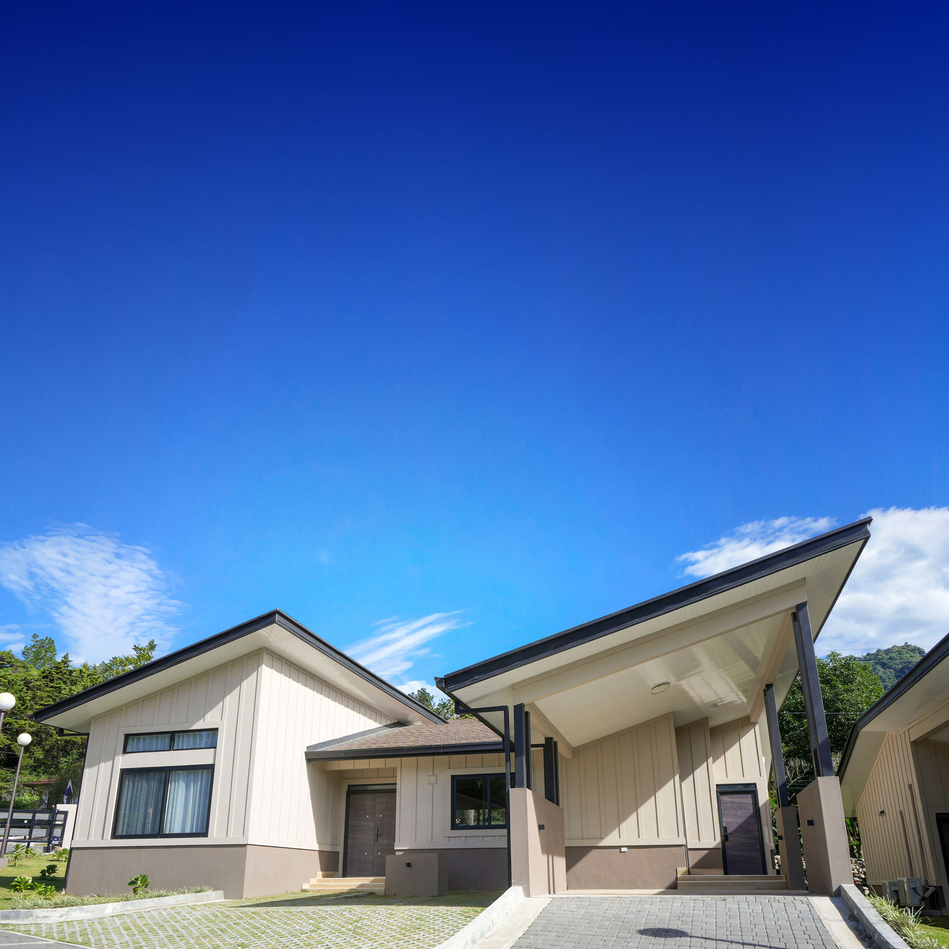 Casa moderna de un nivel con techo inclinado y cielo azul despejado.